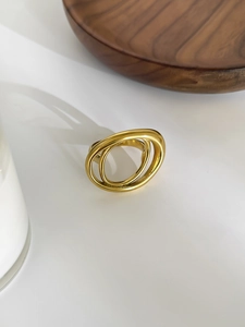 Detail of a minimalist gold-plated double ring with a sleek interlaced design on a white surface