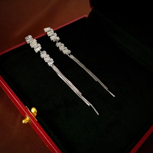 Macro detail of long silver tassel earrings with sparkling zircon stones on red velvet