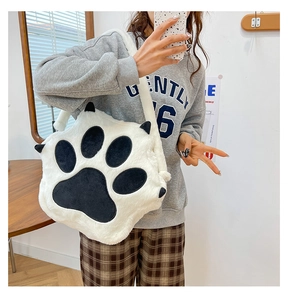 Detail view of the soft white plush cat paw crossbody bag with black pads on a model