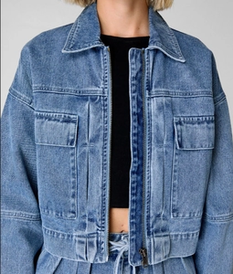 Detail of cropped denim jacket with metal zipper and washed texture in light blue