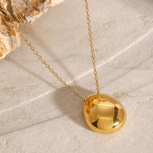 Minimalist gold egg-shaped pendant necklace on stone background, modern polished design