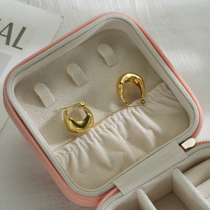 Modern chunky oval hollow gold earrings displayed in a luxury pink jewelry storage box