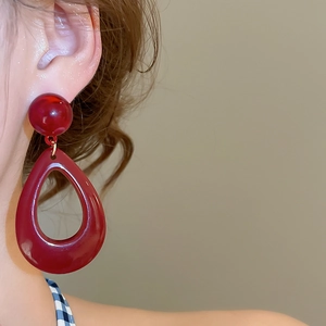 Model wearing deep red resin waterdrop pendant earrings with a vintage minimalist style