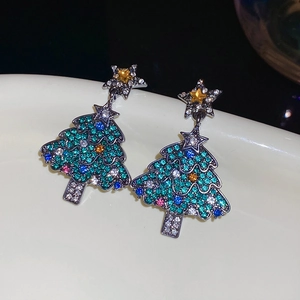 Gros plan de boucles d'oreilles sapin de Noël avec zircons colorés et clous en étoile
