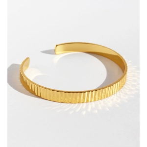 Elegant gold open cuff bracelet with vertical wavy texture and reflective metallic finish