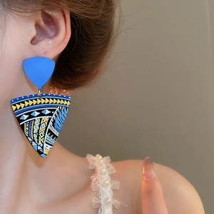 Detailed view of bohemian painted geometric earrings worn by a model in close-up shot