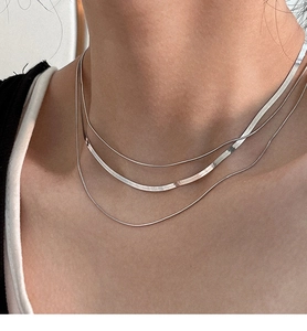 Close-up of triple-layered S925 sterling silver snake chain necklaces on neck