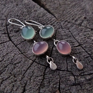 Boucles d'oreilles asymétriques en œil de chat et crochets argentés sur bois sombre
