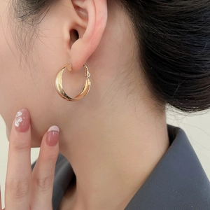 Close-up of a model wearing high-polished gold geometric hoop earrings in a minimalist style
