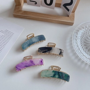 Detail view of 7.5cm rectangle acetate claw clips in four marble patterns with gold metal
