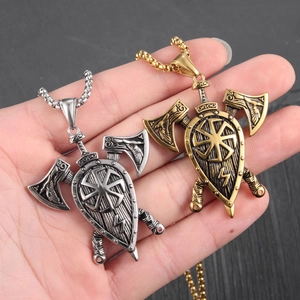 Detail of silver and bronze Viking shield pendants with crossed axes on a wooden background