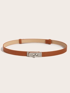 Detail of a thin brown leather belt featuring a silver rhinestone-studded twist lock