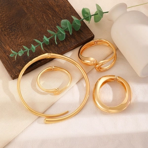 Detail of chunky gold bangle set and collar necklace on natural linen background