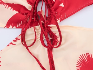 Detailed view of the red and beige palm print dress featuring waist cut-out and lace-up tie
