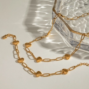 Golden stainless steel heart and paperclip link bracelet with elegant water reflection