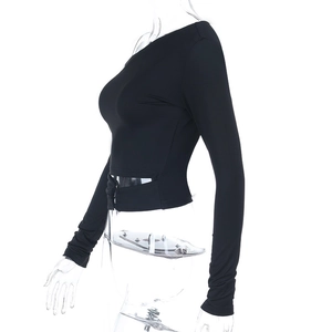 Détail du laçage latéral et du tissu en maille élastique sur un crop top noir à manches