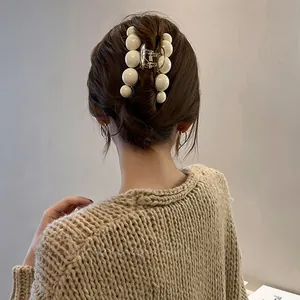 Détail d'une grande pince à cheveux en perles crème portée sur un mannequin élégant