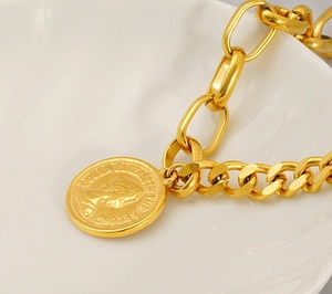 Detailed close-up of a gold-plated Cuban chain bracelet with a Queen coin pendant