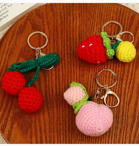Detail of handmade crochet fruit keychains with strawberry, cherry, and peach designs