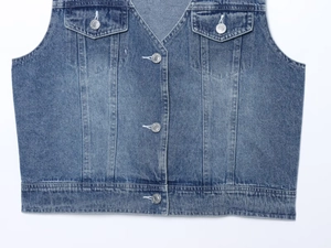 Vue détaillée du gilet en jean montrant le tissu bleu et les coutures de qualité