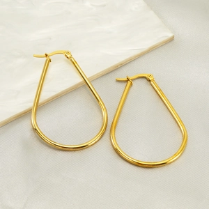 Polished gold teardrop hoop earrings in stainless steel on a marble surface