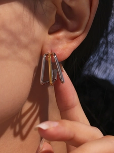 Macro detail of tricolor square U-shaped hoop earrings in polished stainless steel finish
