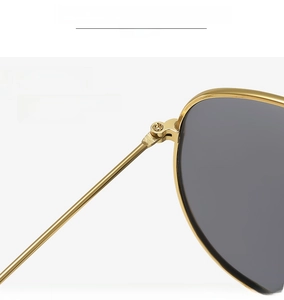 Macro view of a sturdy gold metal hinge and high-quality grey lenses on sunglasses