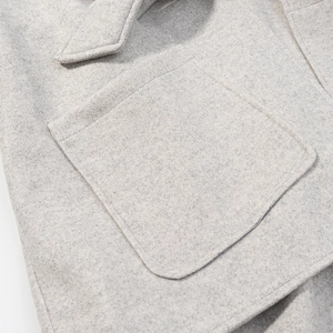 Gros plan sur la texture du tissu en laine grise et la poche plaquée du manteau d'hiver