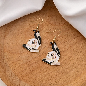 Close-up of gothic crow on skull earrings with oil-drop craft on a wooden tray