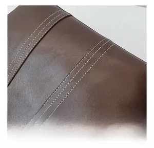 Macro shot of dark brown leather texture and white double-stitch seams on the tote bag