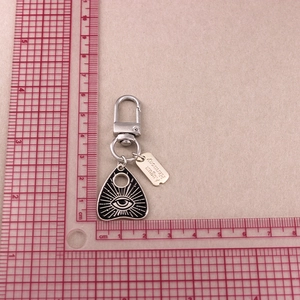 Macro shot of punk spade cat keychain with eye triangle pendant on a cutting mat