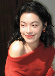 Close-up of red floral earrings and off-shoulder knit top for an elegant winter look