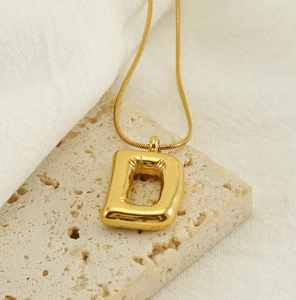 Detail of gold bubble letter D pendant with polished mirror finish on snake chain