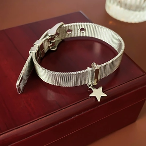 Detail of silver mesh bracelet with star pendant and watch-style buckle on wood box