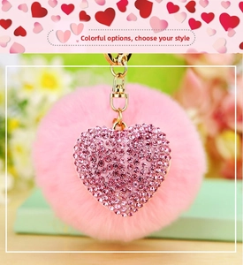 Close-up of heart-shaped pink plush keychain with shimmering purple rhinestones and gold chain