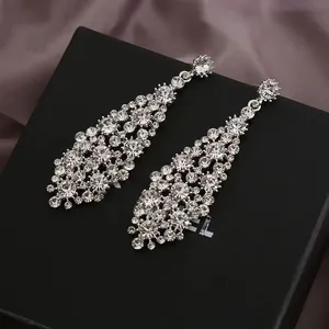 Macro shot of silver dangling earrings with sparkling crystals on black leather display