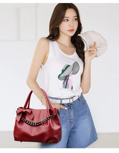 Close-up of wine red PU leather tote bag with elegant bow detail and black chain strap