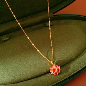 Macro shot of 14k gold plated apple pendant with colorful zircon on green velvet