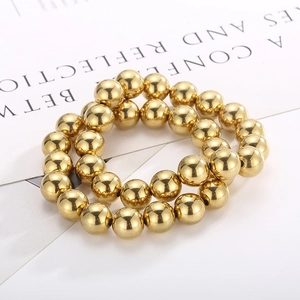 Macro shot of high-polished gold beaded stretch bracelet on a minimalist magazine background