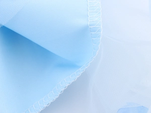 Macro shot of light blue tulle fabric with detailed edge stitching for a fairy maxi dress