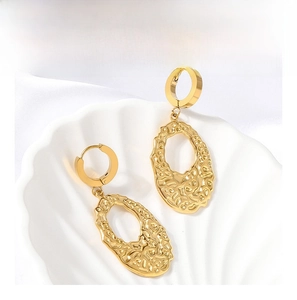 Detail of gold irregular hammered oval earrings on a shell with silk background