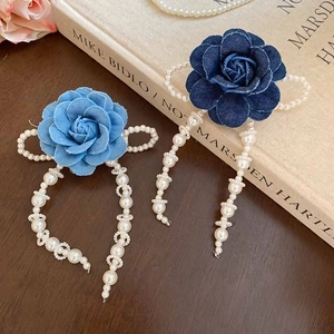 Detail of vintage fabric rose hair clips with dangling pearl tassels on antique books