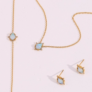 Detail shot of gold-plated jewelry set with teardrop opal stones and zircon accents