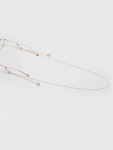 Detail of gold metal eyewear chain with white pearls and silicone anti-slip loops
