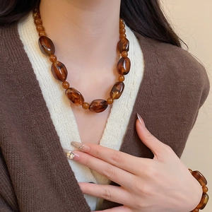 Close-up of amber irregular acrylic beaded necklace and bracelet set on a model