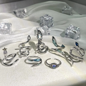 Silver snake rings set with blue gemstones on white silk background with ice cubes