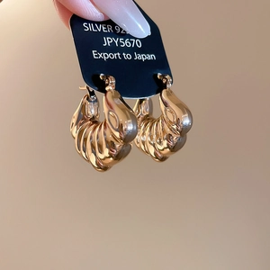 Macro shot of 925 silver shell-texture hoop earrings with polished golden finish