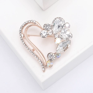 Elegant gold heart brooch with sparkling rhinestones on a minimalist white cube pedestal
