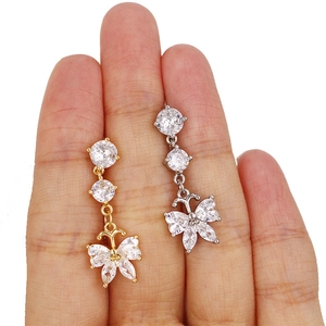 Détail de boucles d'oreilles papillon dorées et argentées avec zircons étincelants