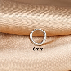 Macro shot of 6mm polished silver mini hoop earring on champagne silk background